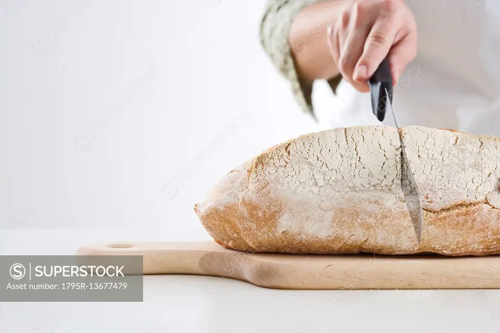 Hand cutting loaf of bread