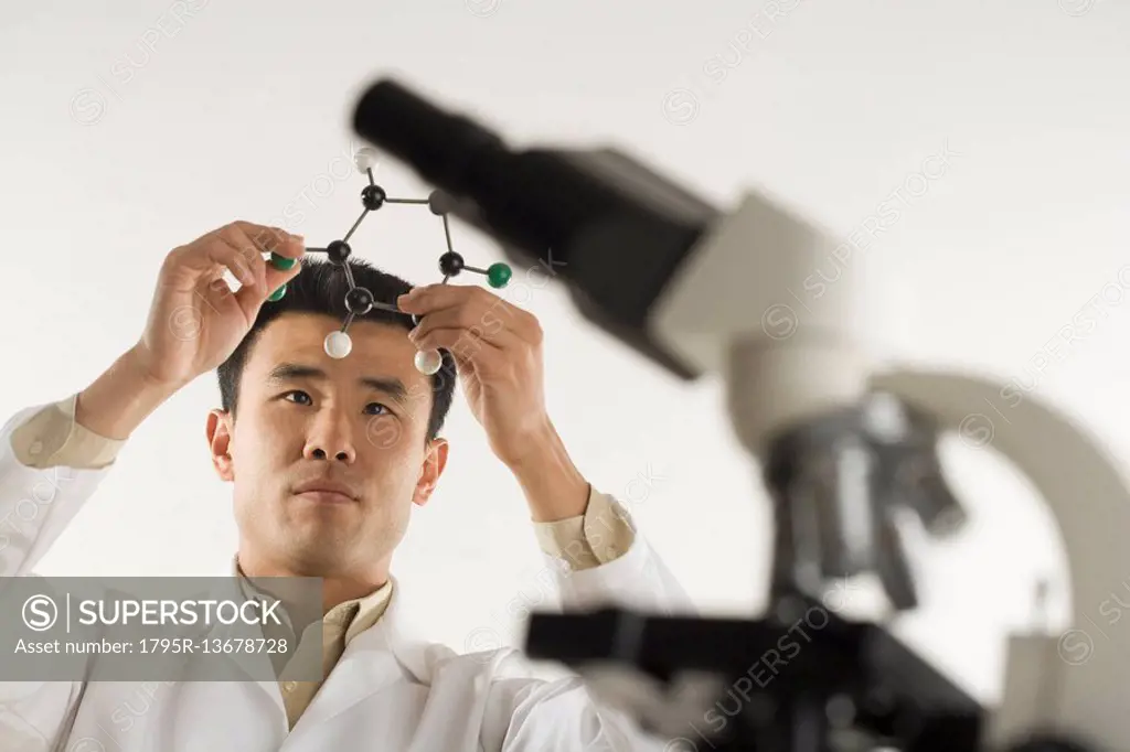 Scientist with microscope holding molecular model