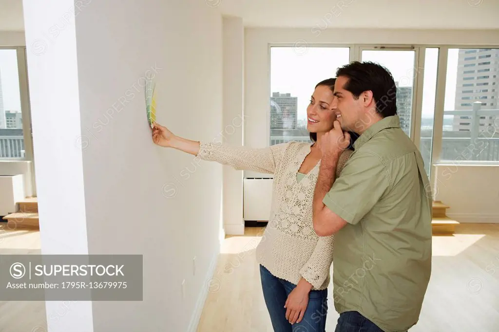 Couple holding paint swatches up to wall