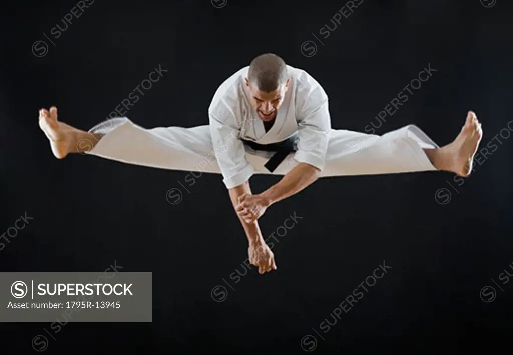 Hispanic male karate black belt jumping in air