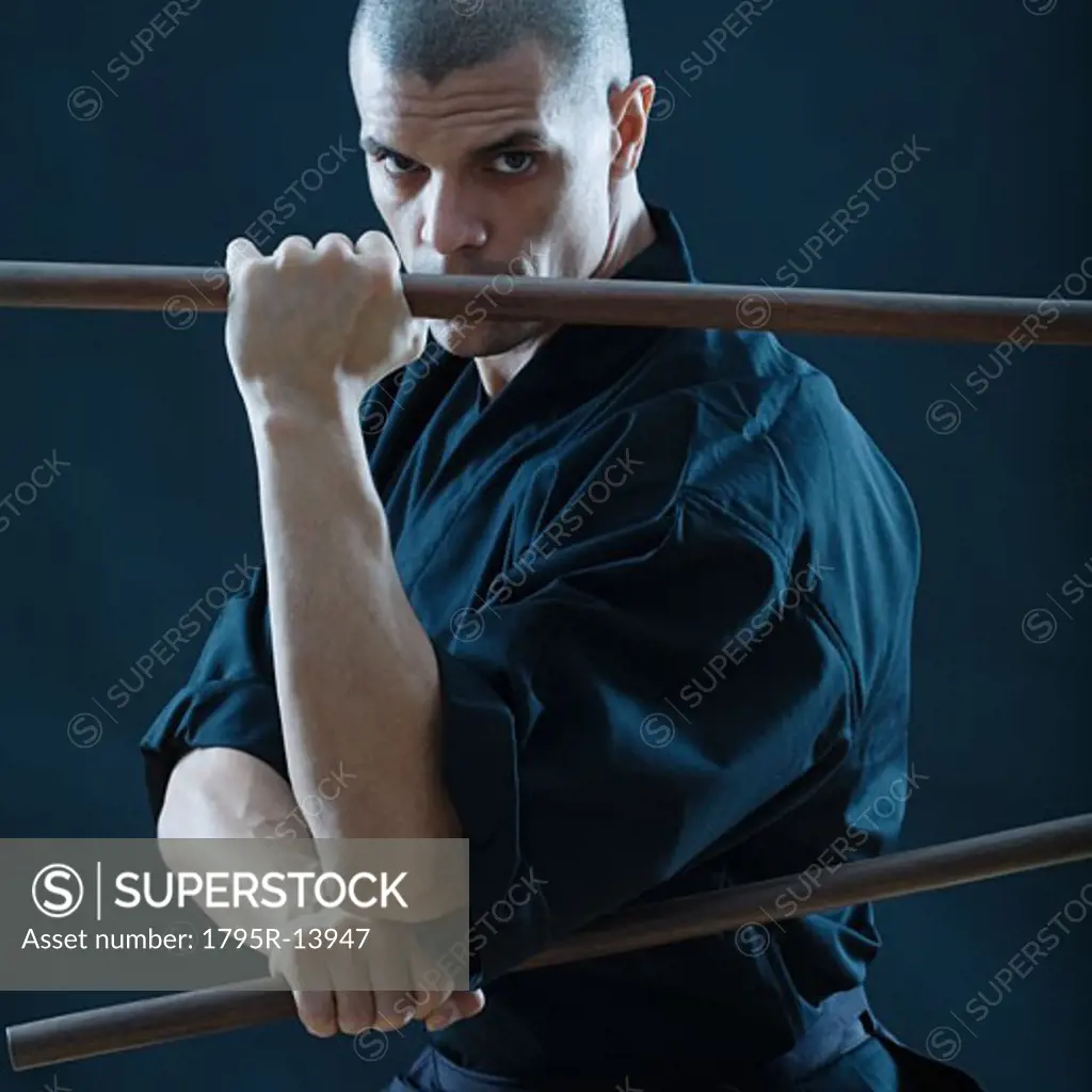 Hispanic male holding sticks in fighting stance