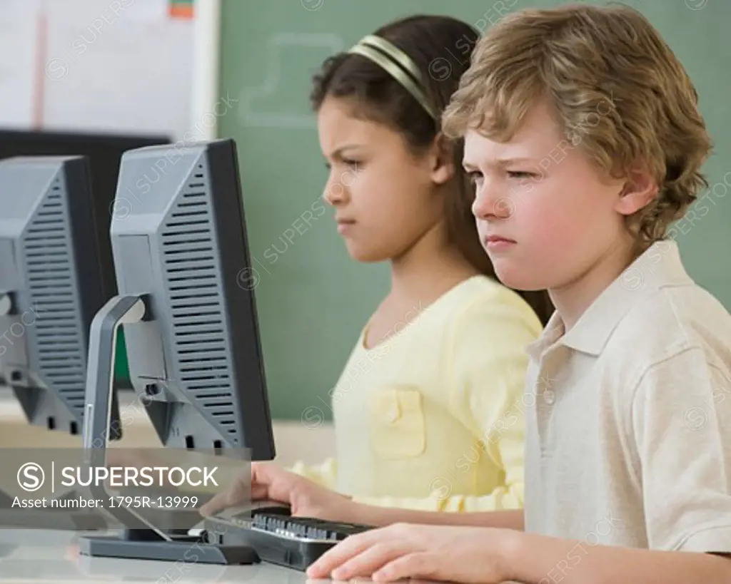 Multi-ethnic school children looking at computers