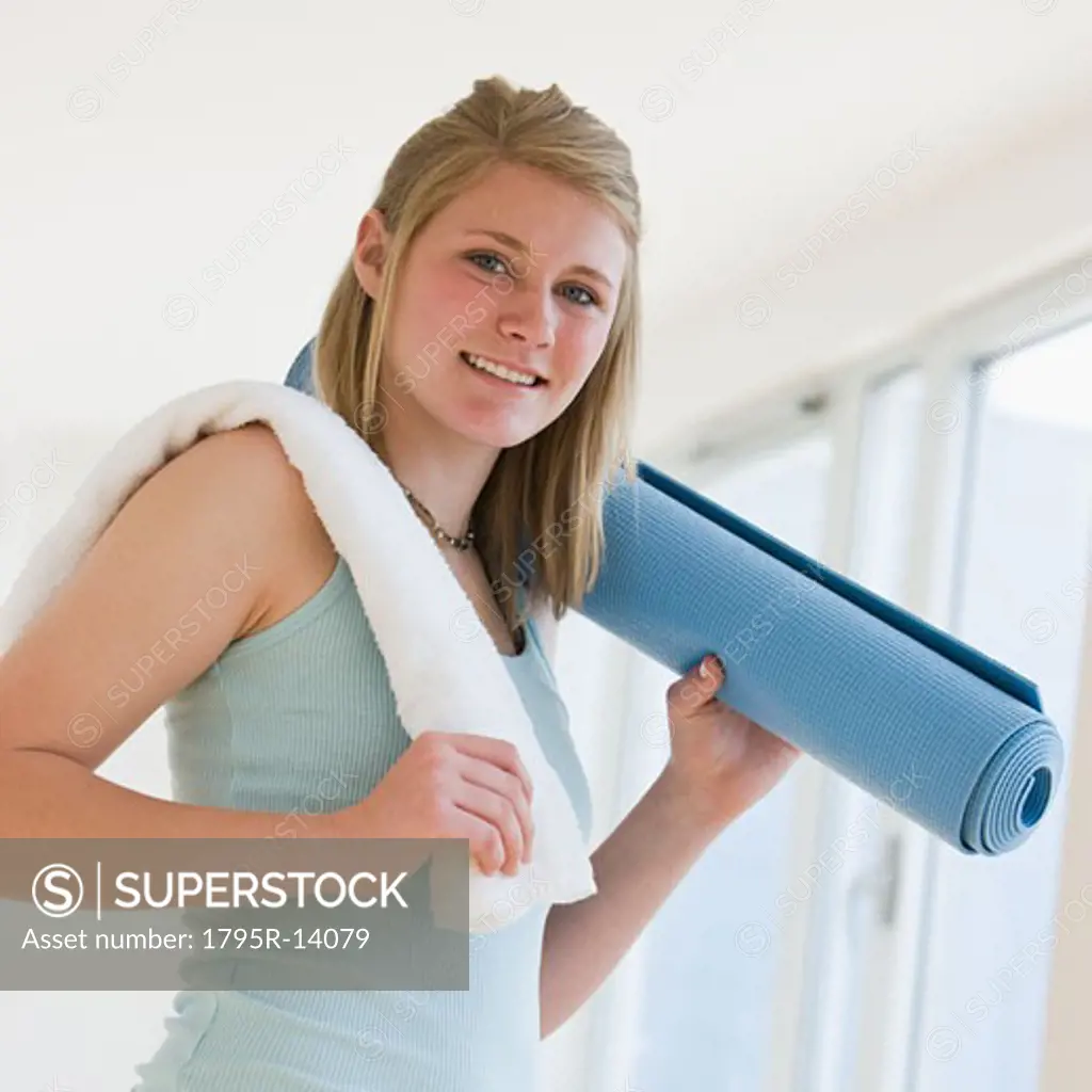 Teenaged girl holding rolled yoga mat