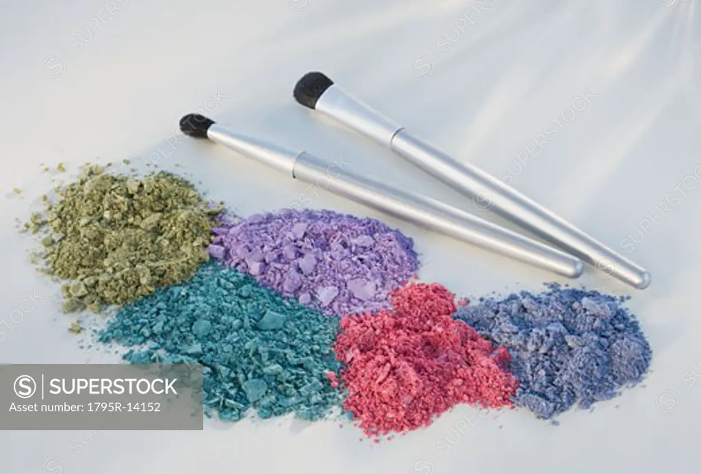 Assorted crushed cosmetics next to brushes