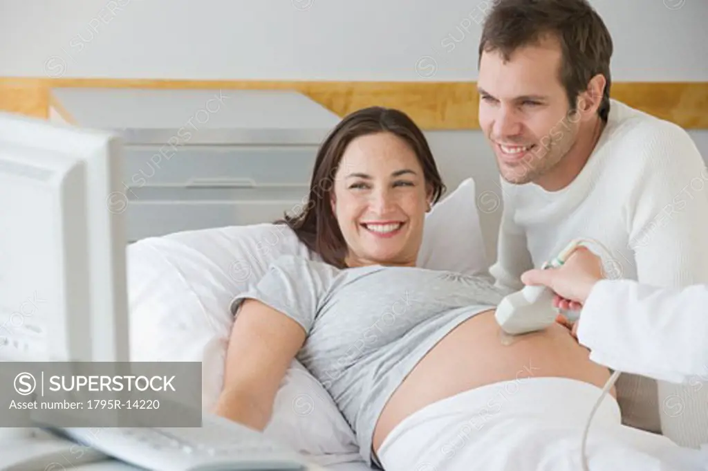 Pregnant Hispanic couple looking at ultrasound monitor