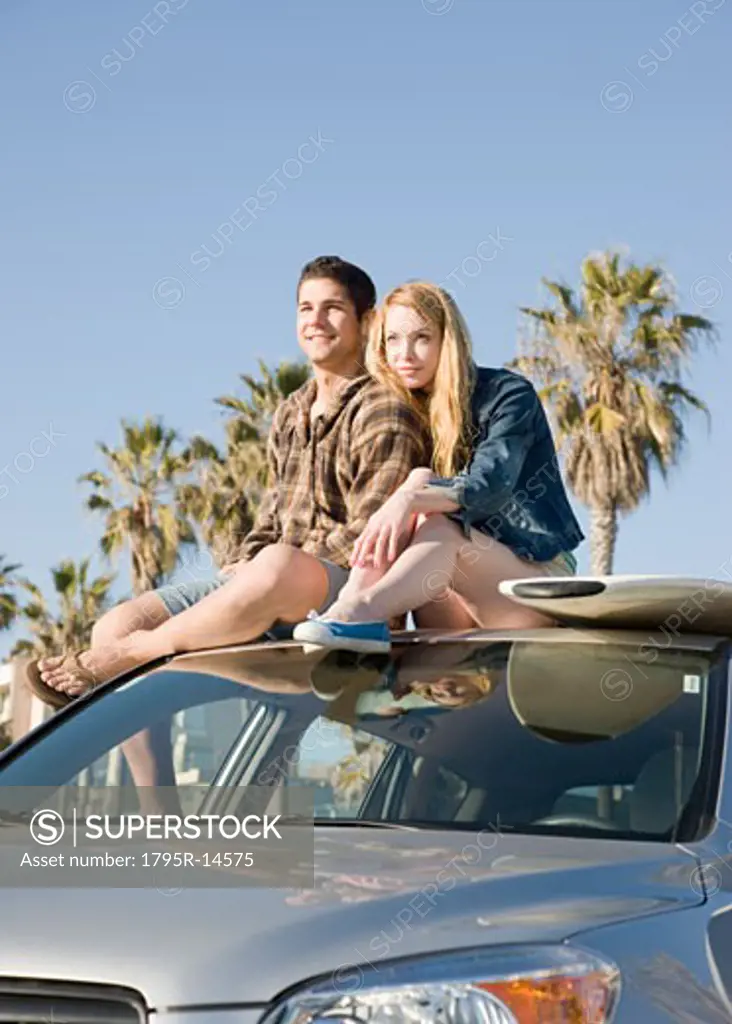 Couple sitting on top of car