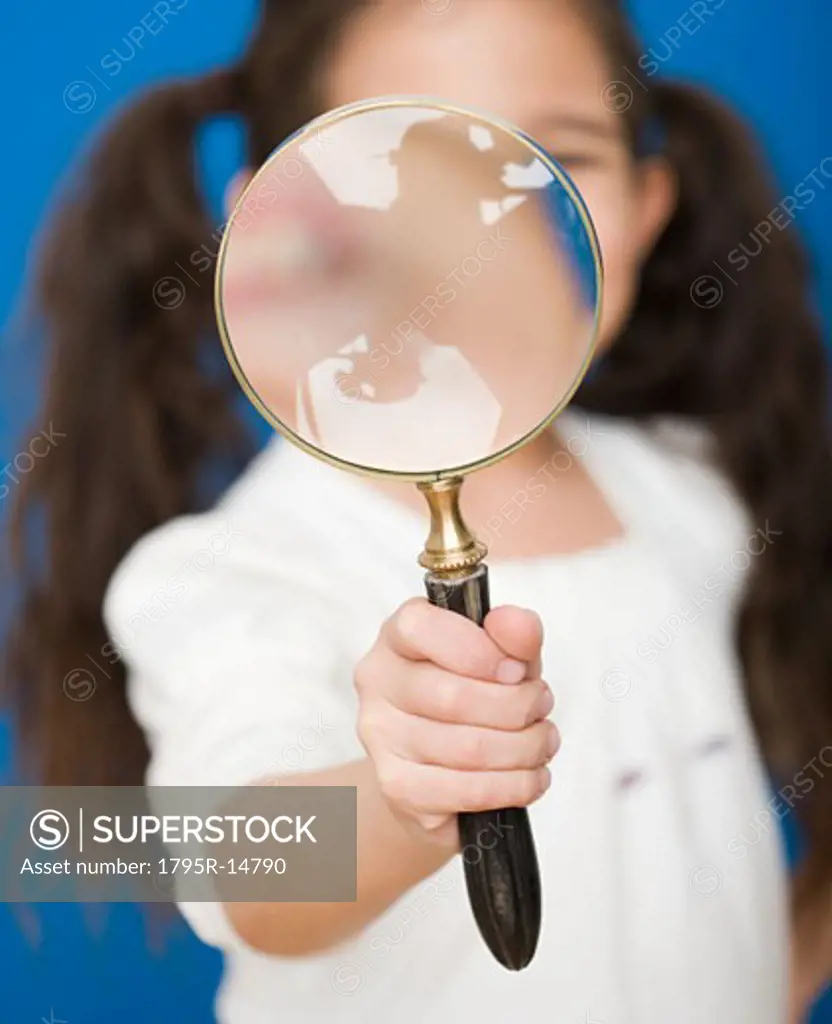 Hispanic girl holding magnifying glass
