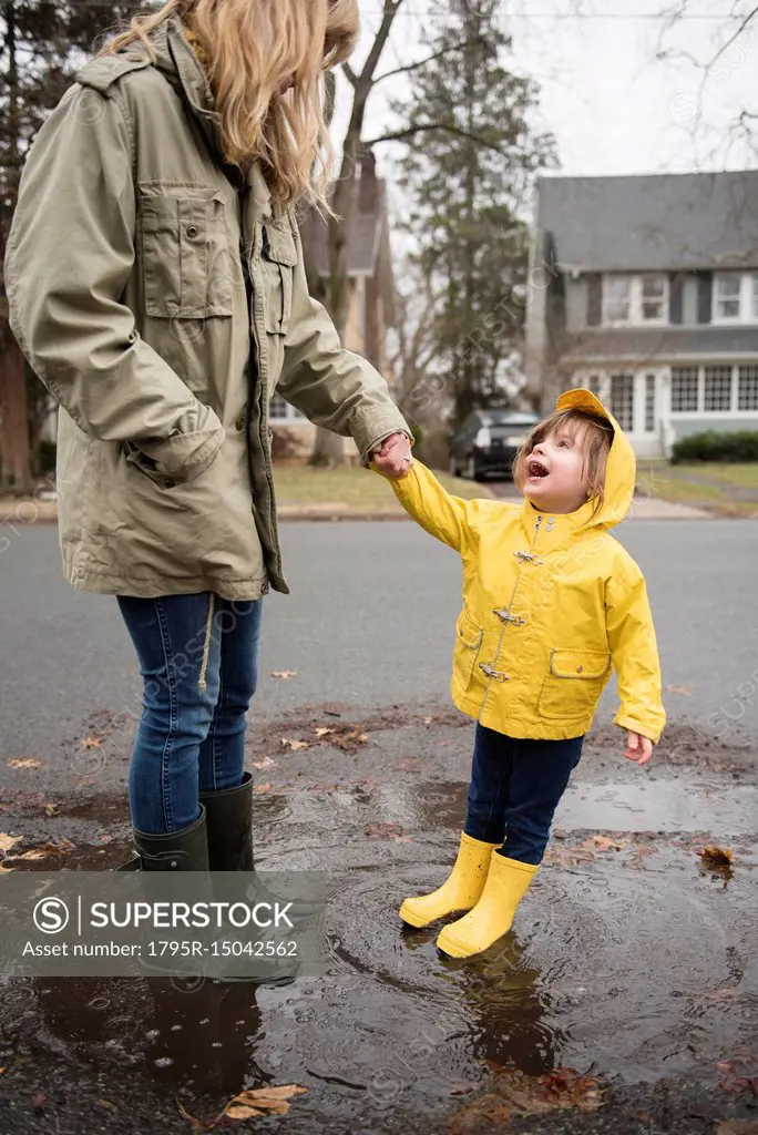 Mother and daughter (2-3) in puddle