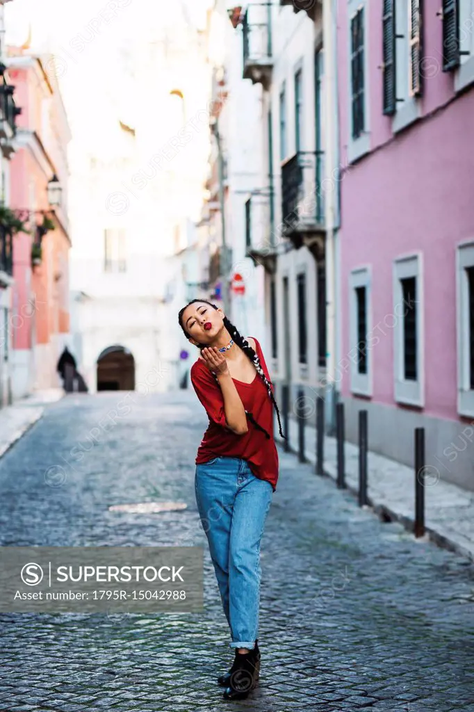 Portugal, Lisbon, Young woman blowing kiss in old town