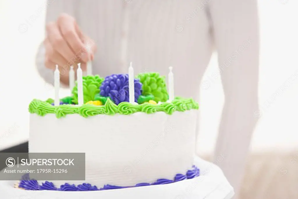 Woman putting candle on birthday cake