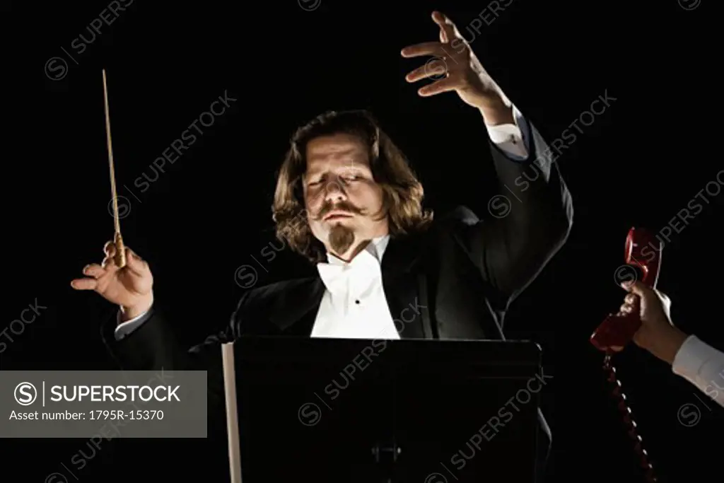 Telephone being handed to orchestral conductor