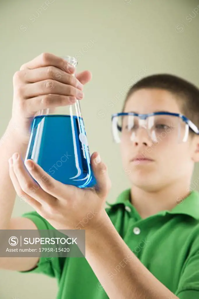 Boy looking at beaker of liquid