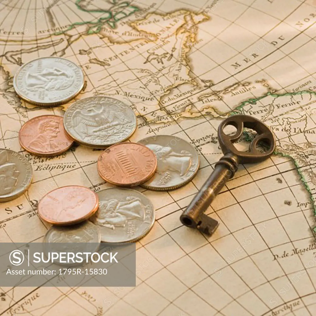 Close-up of coins and key on map