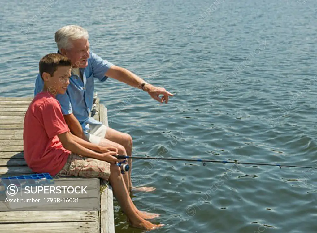 Grandfather and grandson fishing off dock