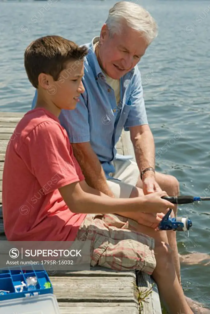 Grandfather and grandson fishing off dock