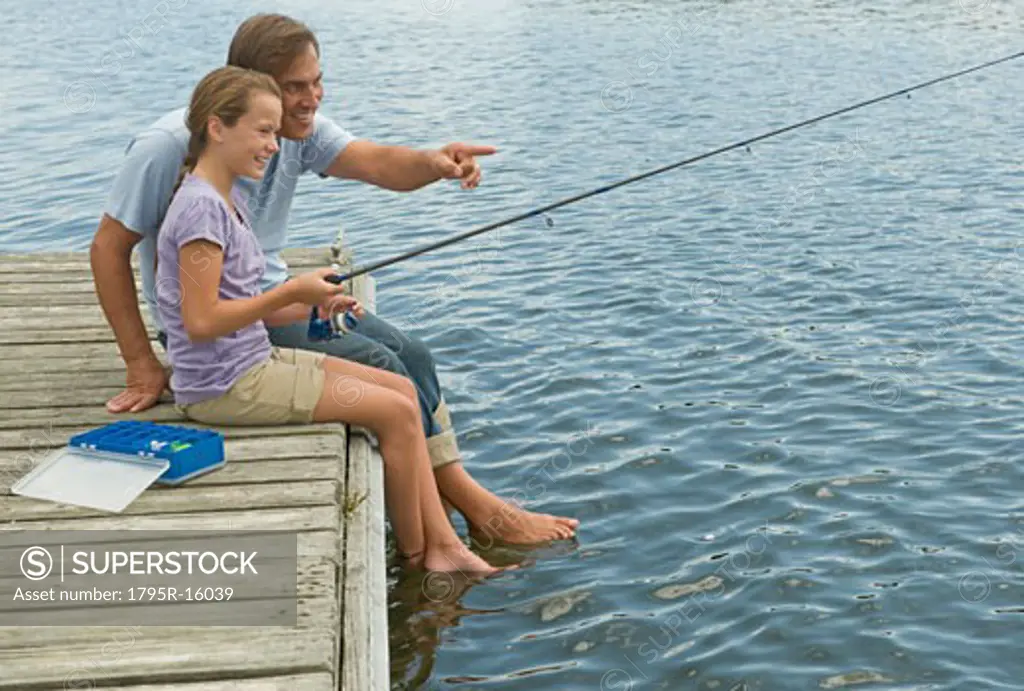 Father and daughter fishing off dock