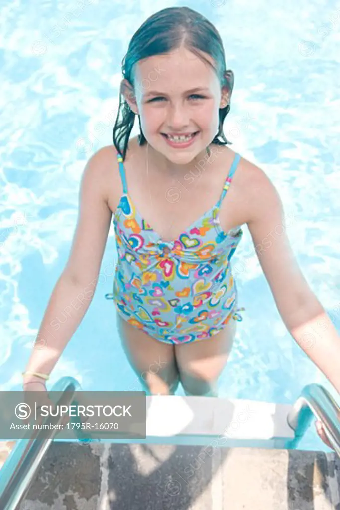 Girl standing on swimming pool ladder