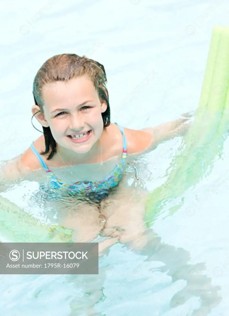 Girl playing on inflatable raft in swimming pool