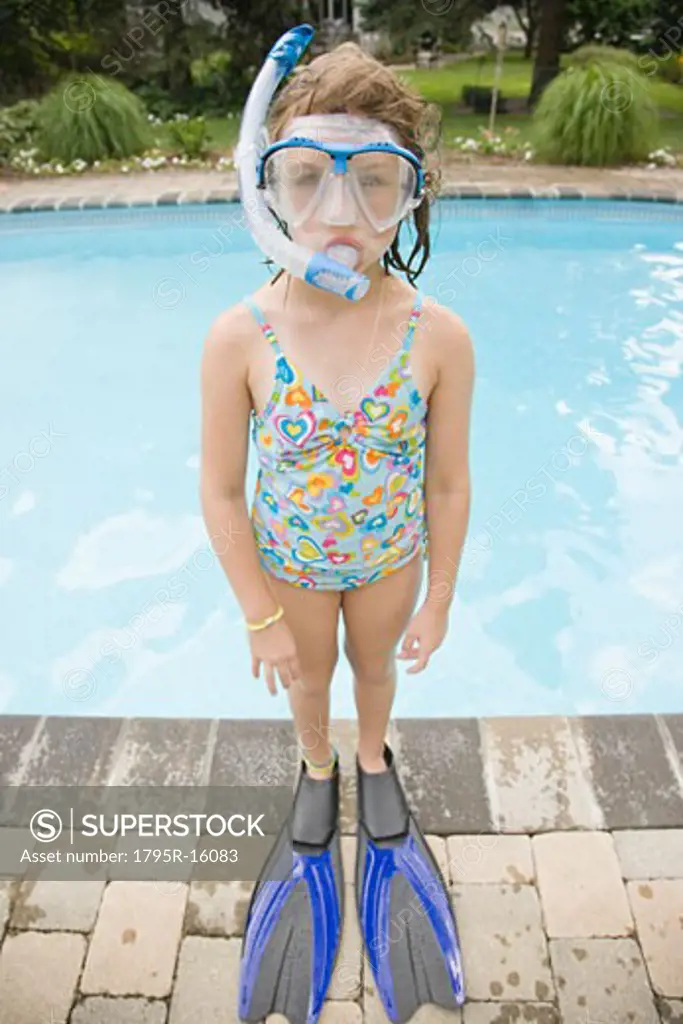 Girl in snorkeling gear standing at edge of swimming pool