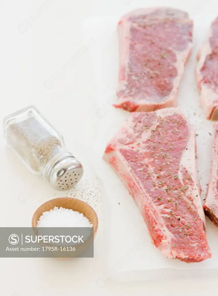 Close-up of raw steaks and seasoning