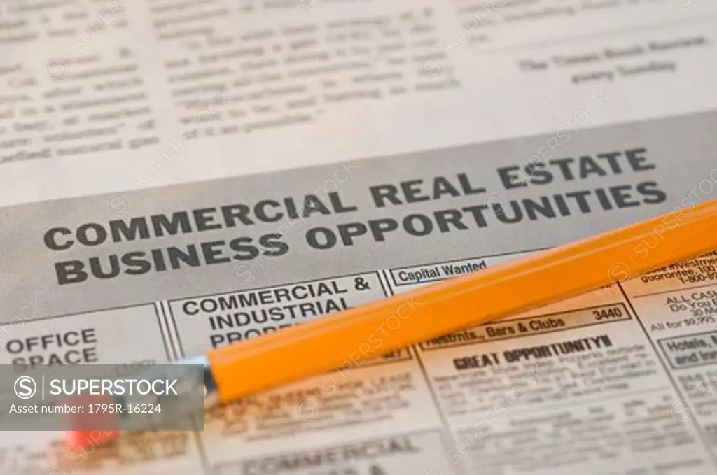 Close-up of pencil and real estate newspaper ads