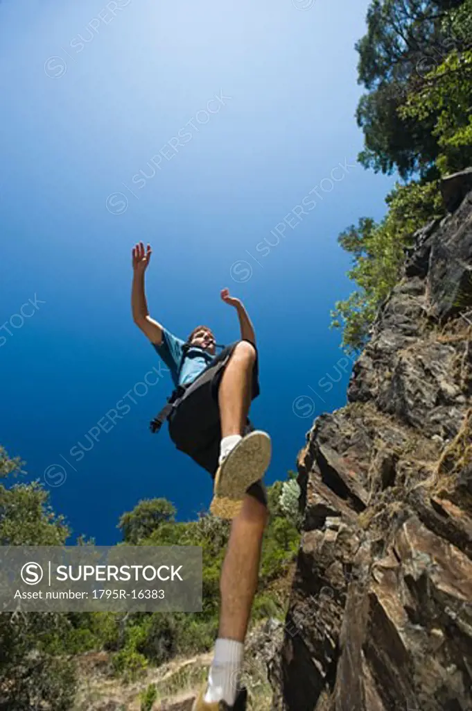 Hiker jumping down rocky trail