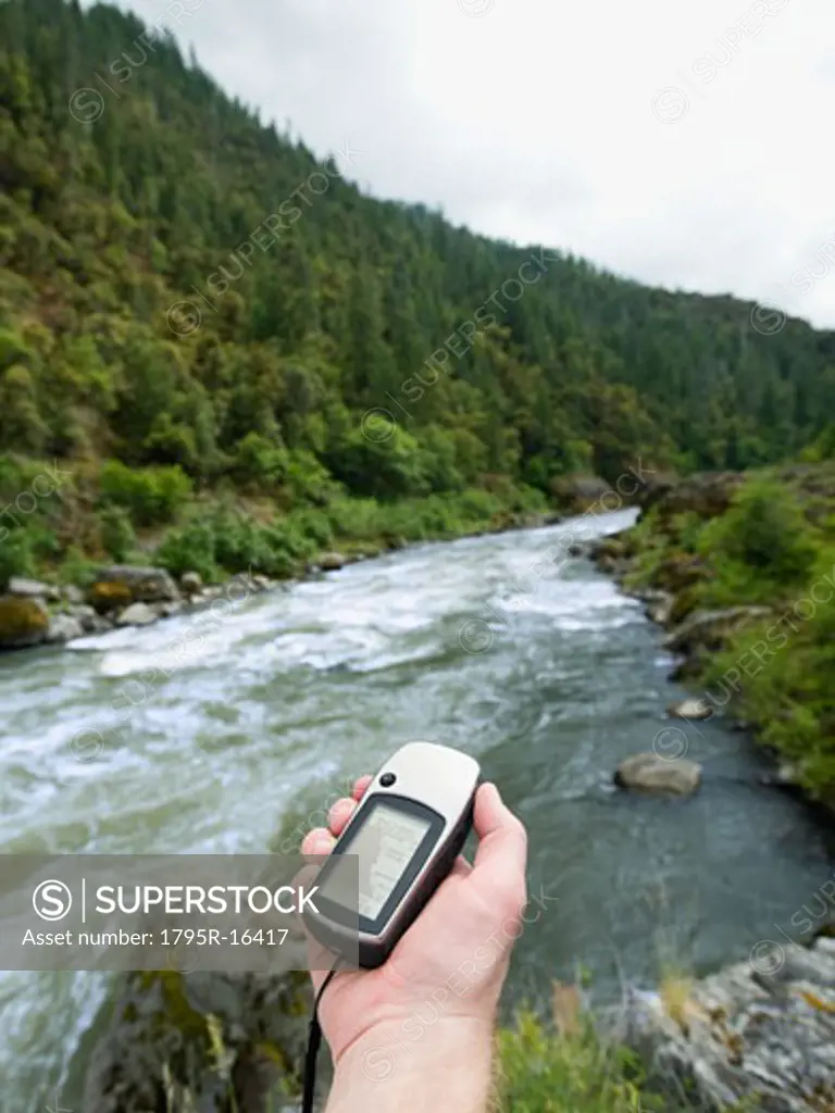 Man holding gps unit by river