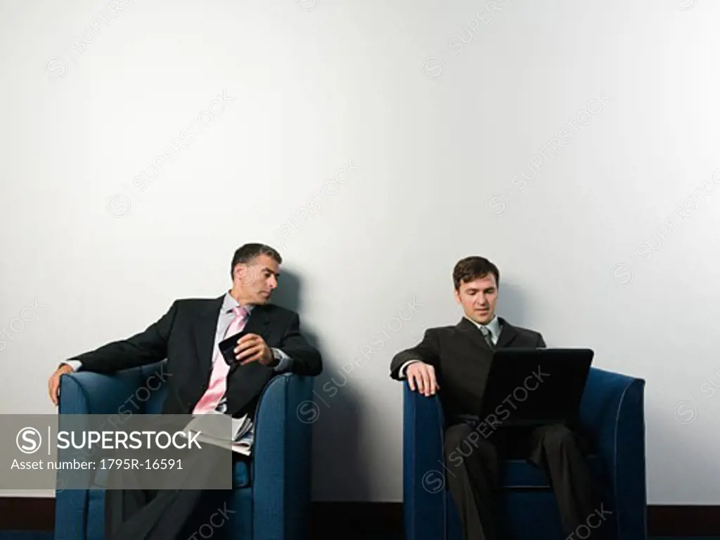 Businessmen sitting in chairs in office lobby