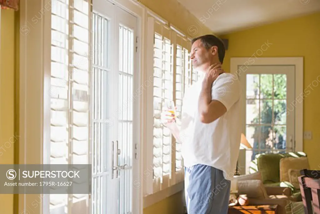 Man in pajamas looking out window