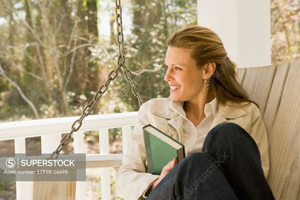 Woman relaxing with book on porch swing