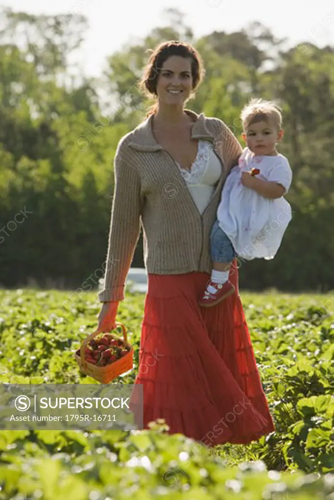 Mother and baby daughter picking strawberries