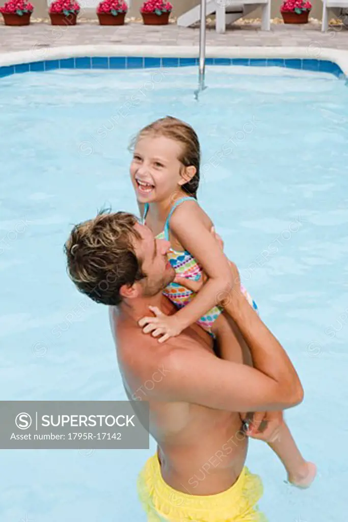 Father lifting daughter out of swimming pool