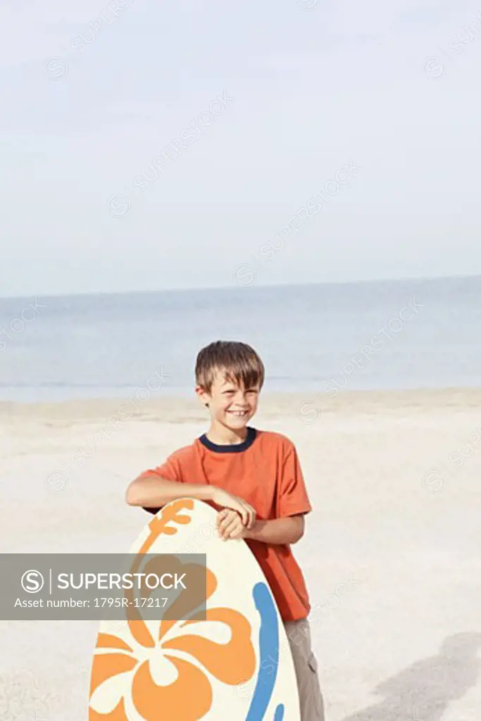 Boy holding skimboard on beach