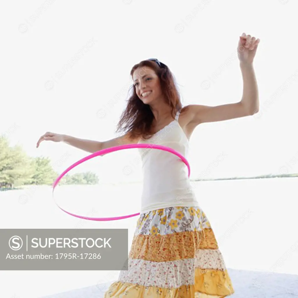 Young woman hula hooping on beach