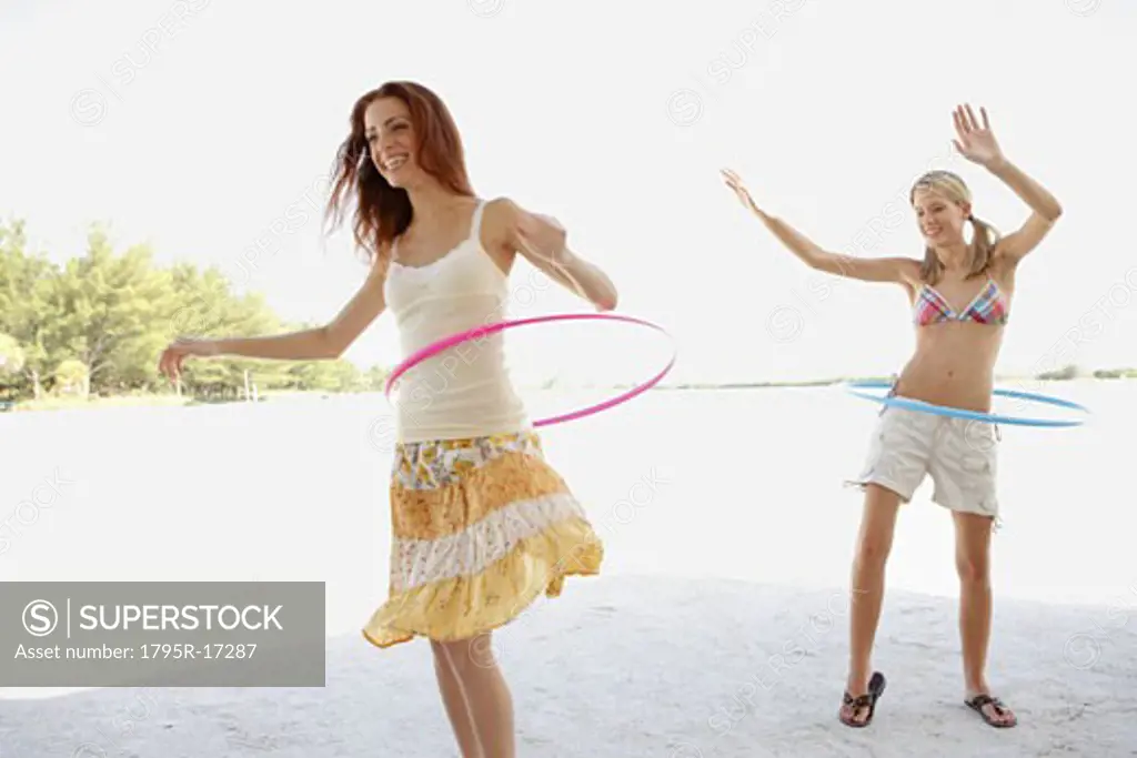 Young women hula hooping on beach