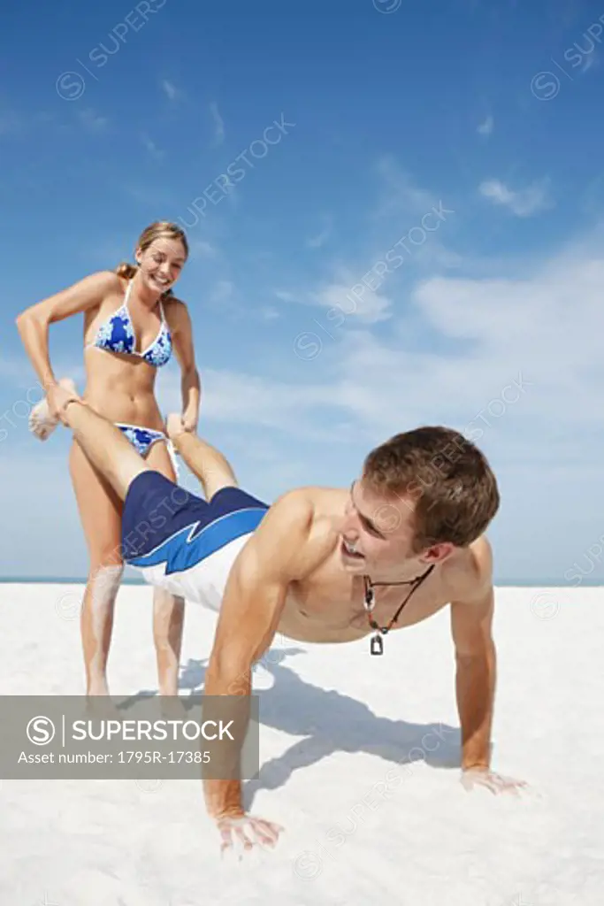 Teenage girl pushing boyfriend on beach
