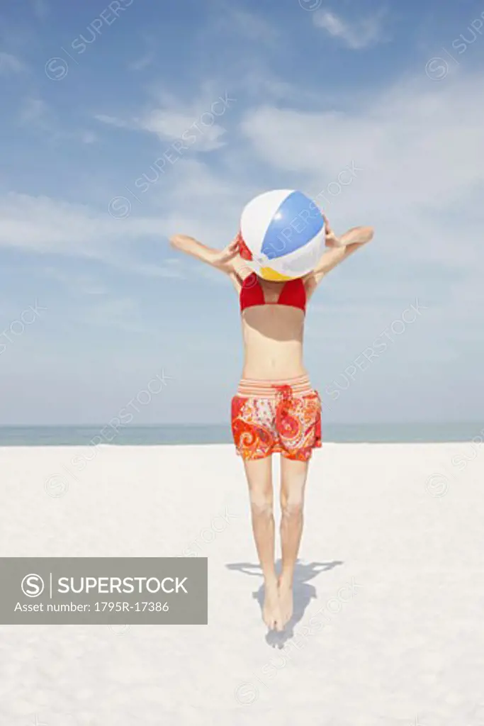 Young woman jumping with beach ball