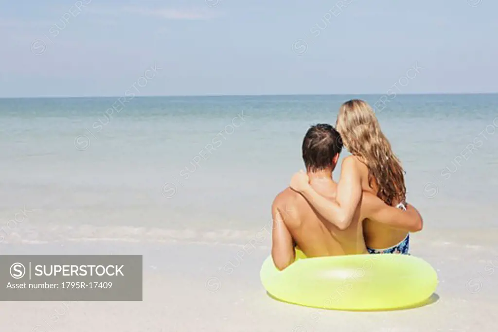 Couple sitting in inflatable ring in shallow ocean