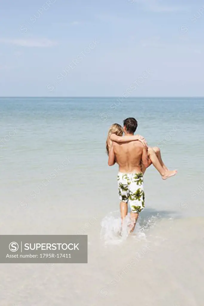 Teenage boy carrying girlfriend in ocean