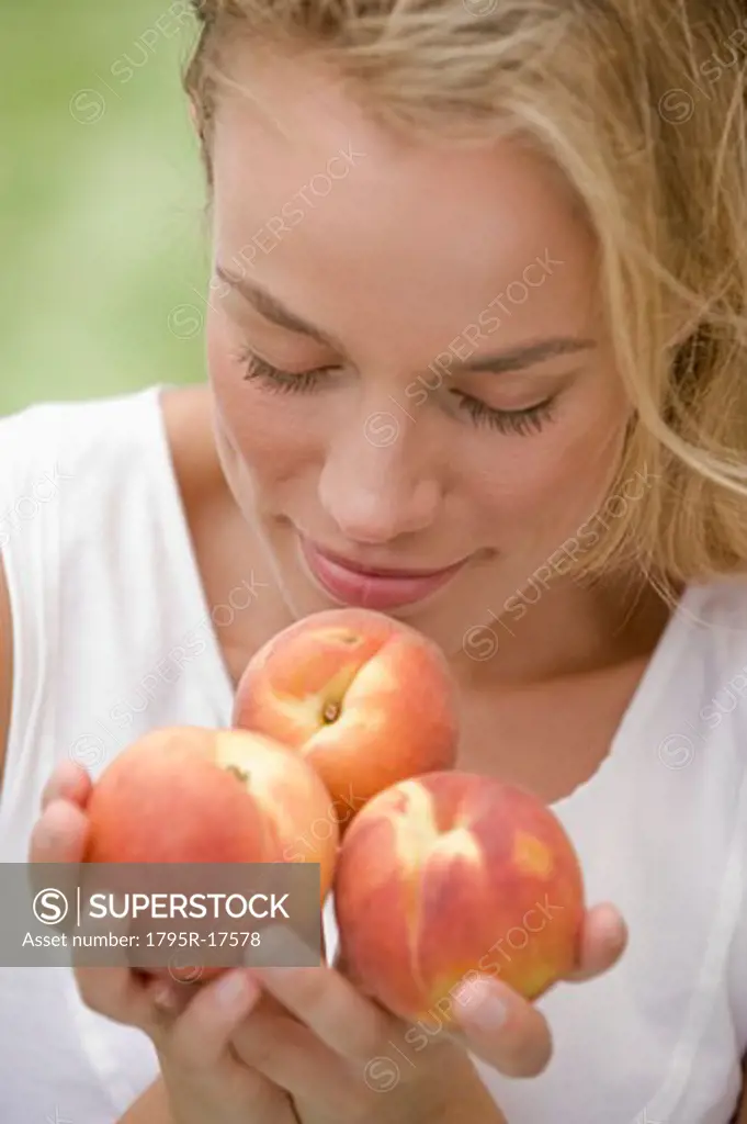 Woman smelling fresh peaches