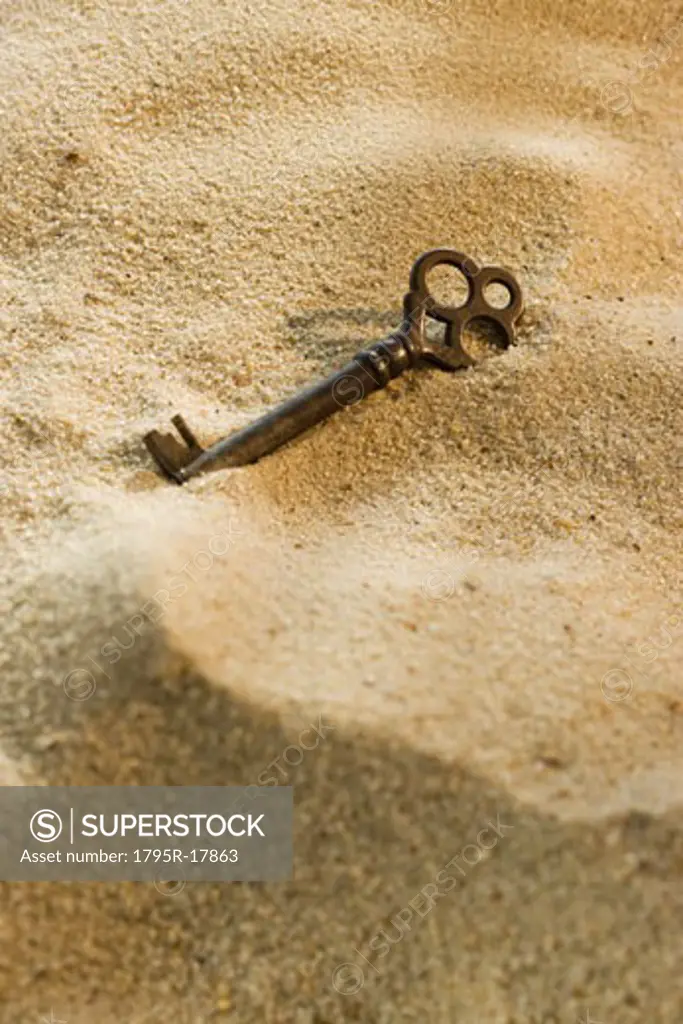 Close-up of old-fashioned key in sand