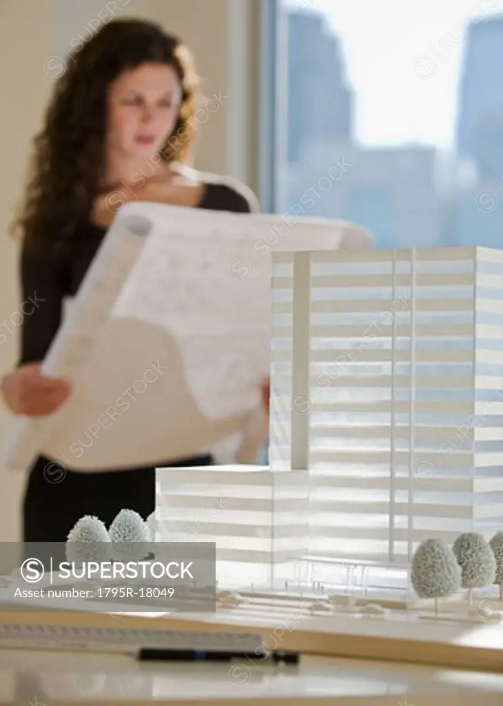 Architect viewing blueprints near building model