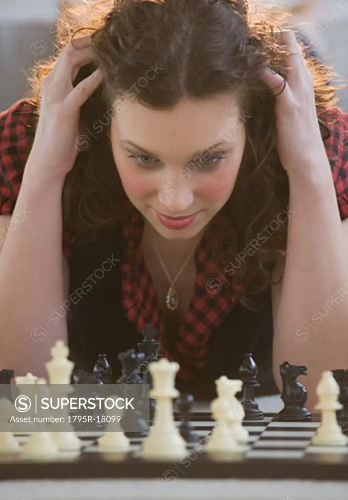Close-up of woman looking down at chessboard