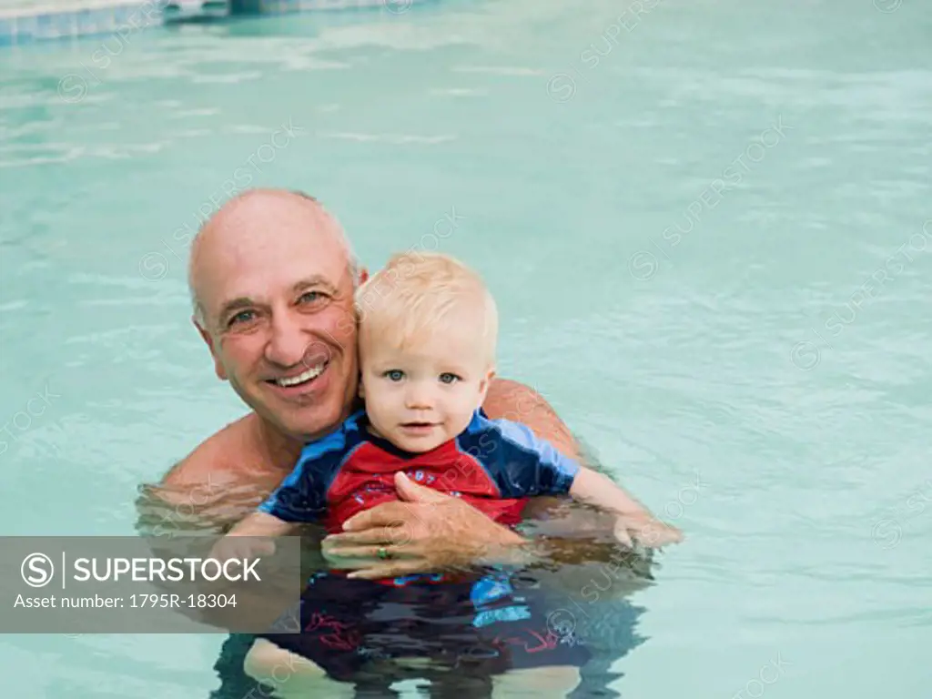 Grandfather and grandson posing in swimming pool