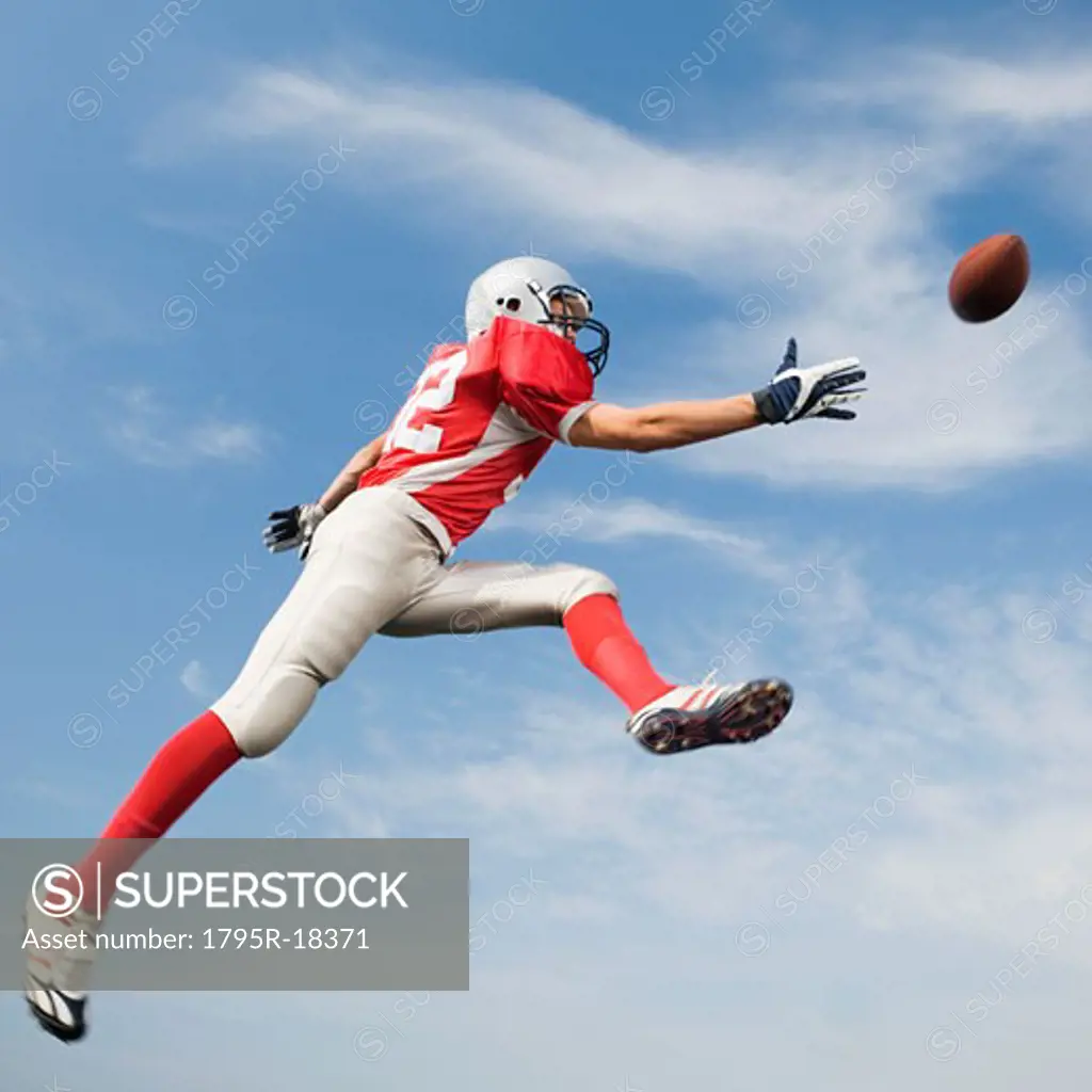 Football player in mid-air reaching for football
