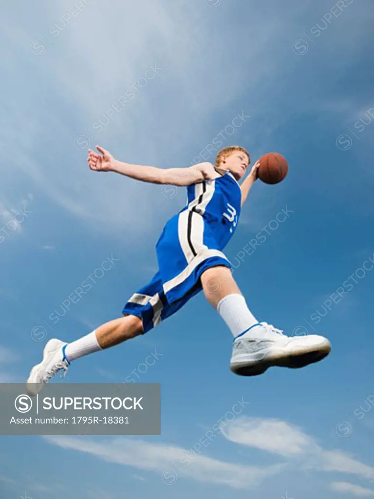 Teenage basketball player in mid-air with basketball