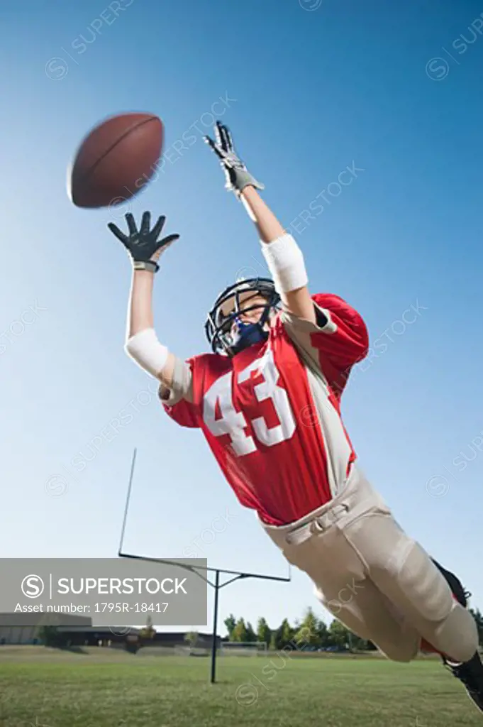 Football player in mid-air reaching for football