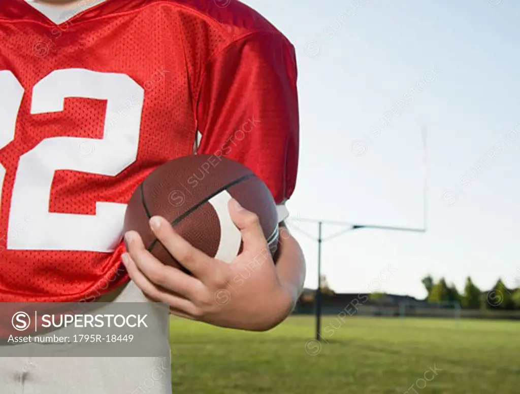 Close-up of football player holding football on field