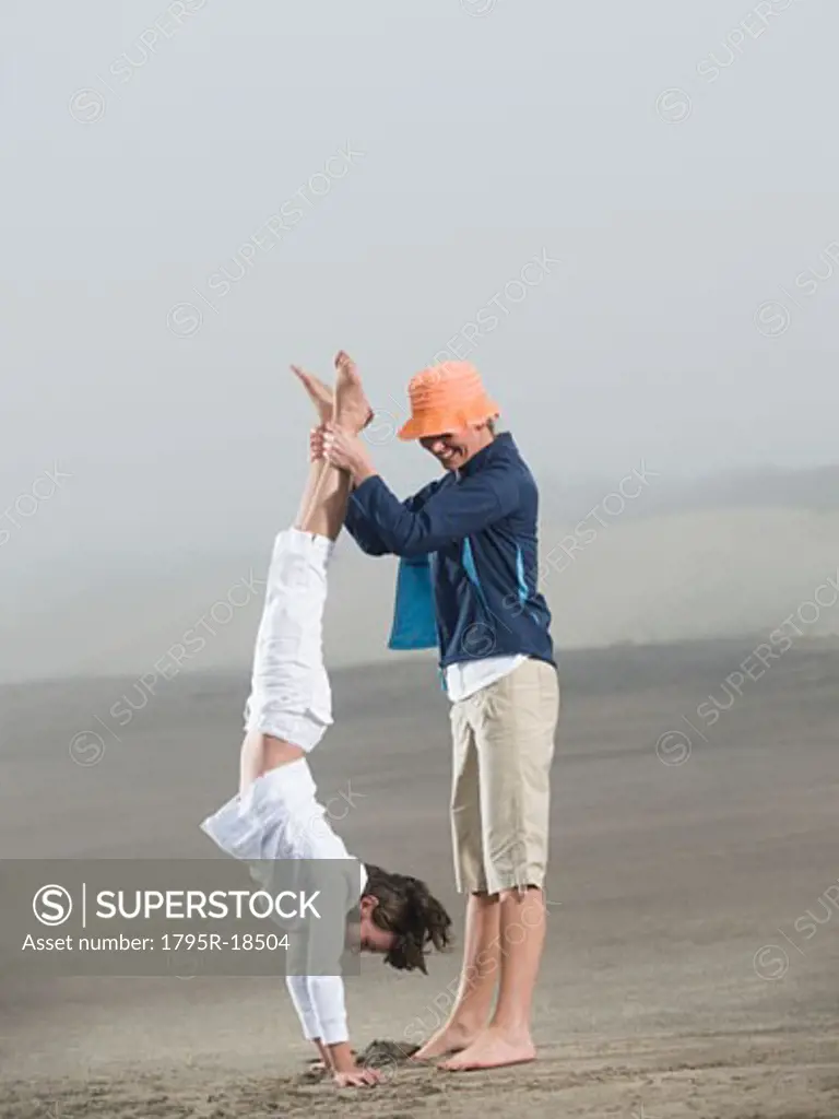 Mother holding daughter upside down on beach