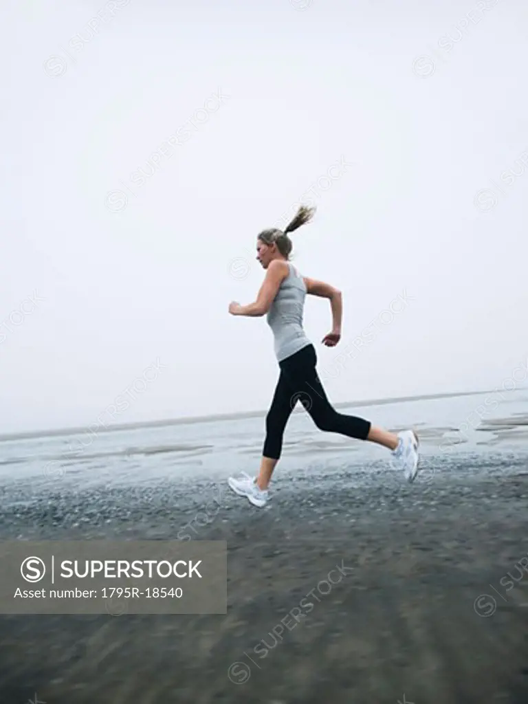 Woman jogging on foggy beach